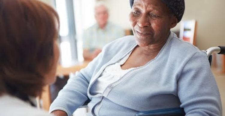 Black elderly woman ina nursing home being spoken to by a nurse